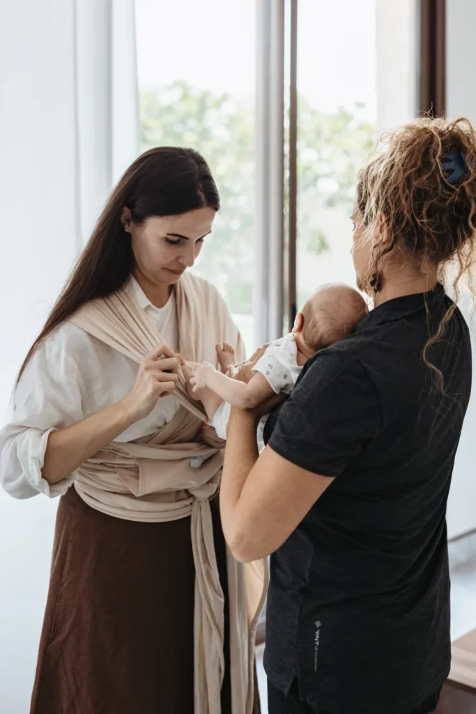 Silvia helps a mother position her baby in a fabric wrap.
